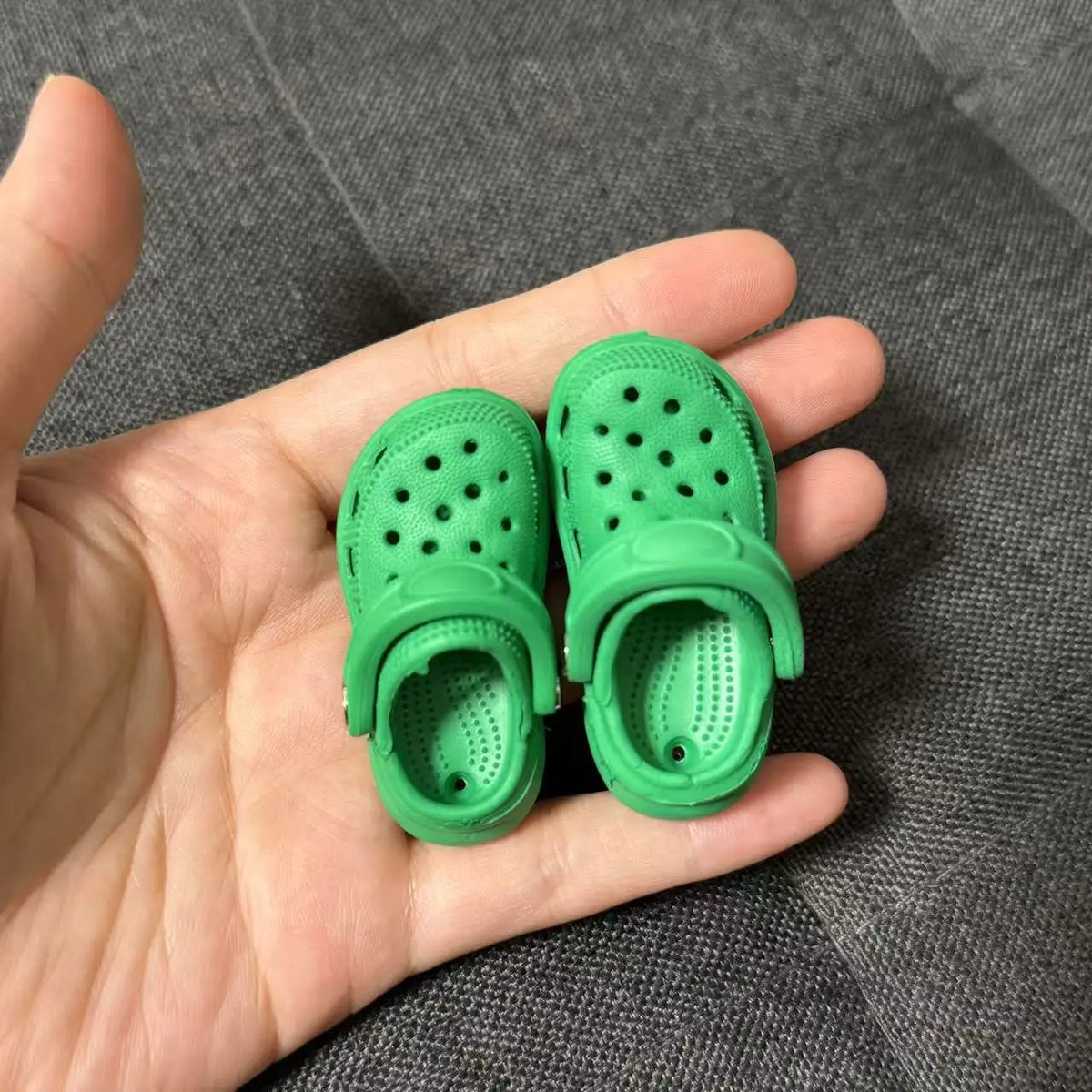 A pair of bright green fashion slippers designed for 1/6 BJD dolls, shown in a hand.