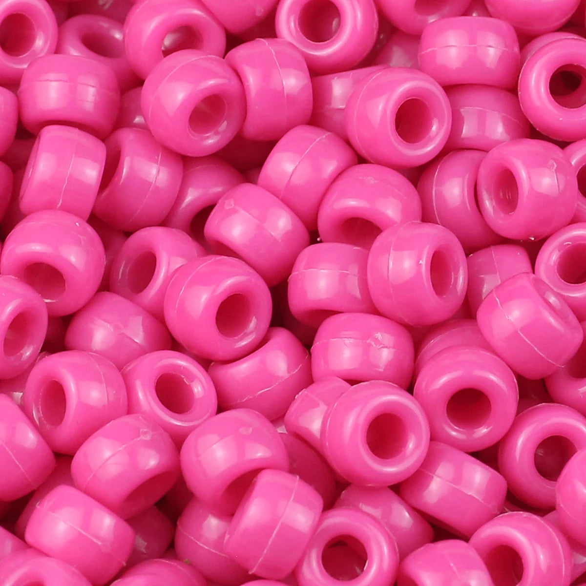 A close-up view of small, pink plastic pony beads for jewelry making and crafts.