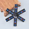 A black metal fidget spinner with a rainbow finish is held by a person's hand.