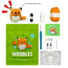 A green pouch containing a wool and needle crochet kit for beginners, with an orange fox toy visible.