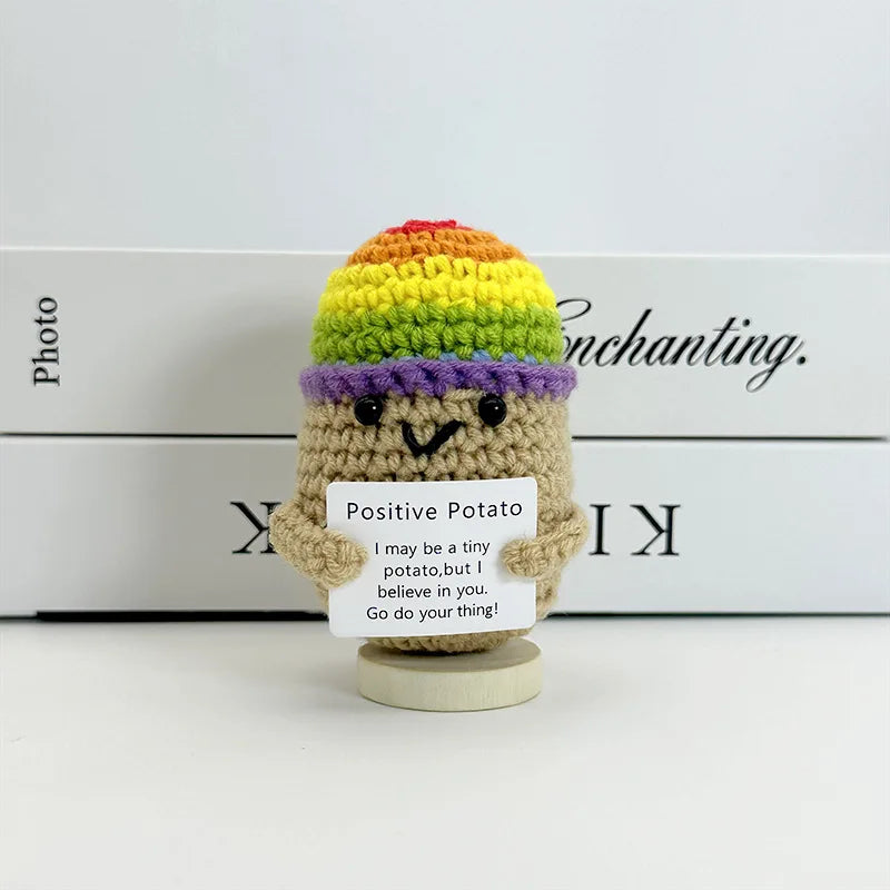 A handwoven crochet potato ornament with colorful yarn layers, sitting on a wooden base.