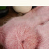Close-up of fluffy pink knitted yarn being used for handmade knitting.