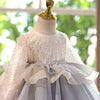 A white tulle princess dress displayed on a mannequin with a gold figurine topper.