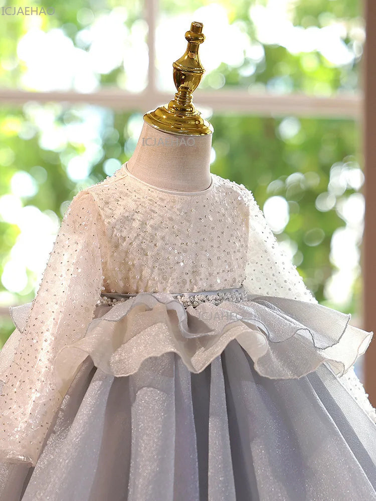 A white tulle princess dress displayed on a mannequin with a gold figurine topper.