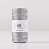 A spool of metallic gray yarn for knitting and crochet with a white label featuring the brand name and a happy handmade life 