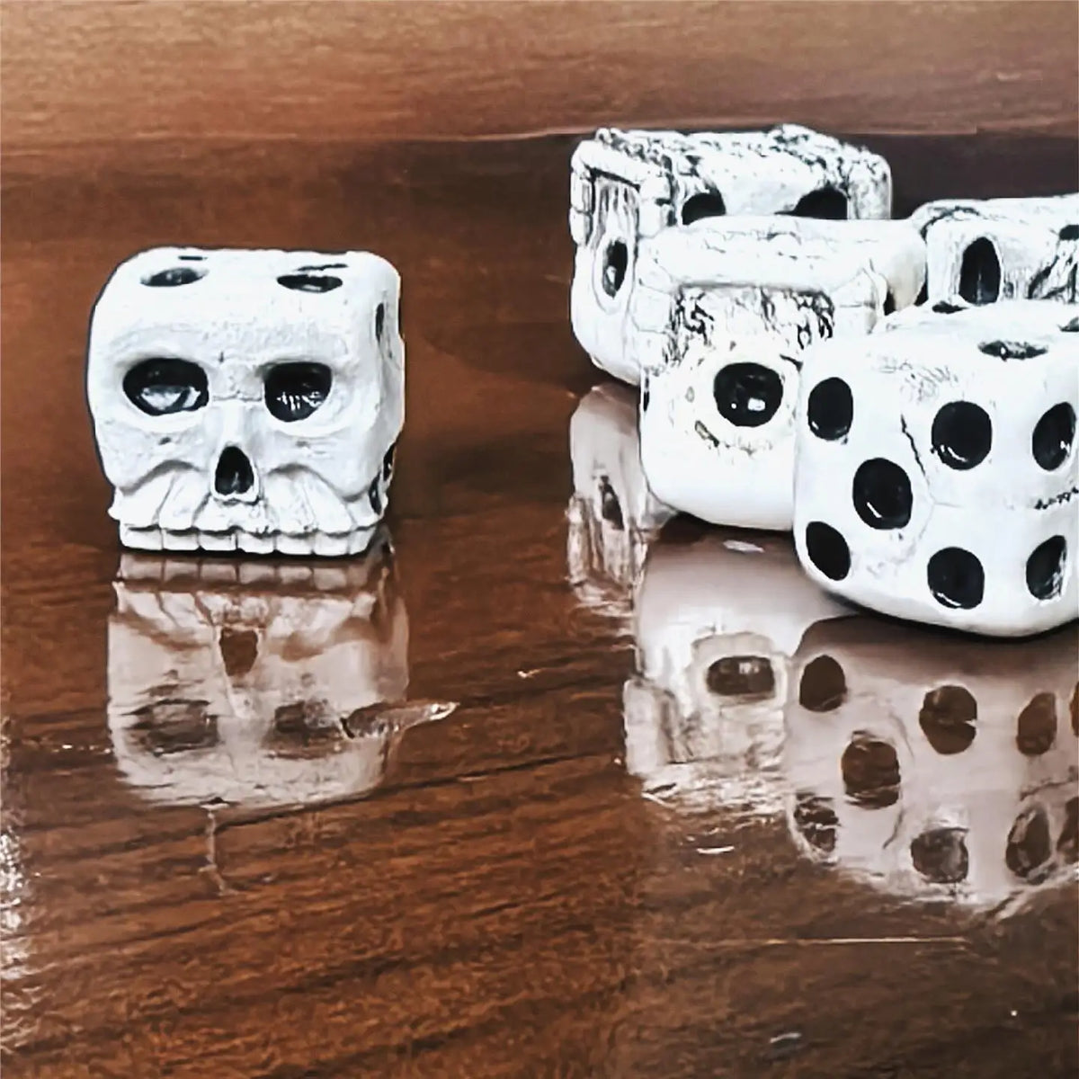 A set of white skull dice, used for Halloween and party games, are displayed on a wooden surface.