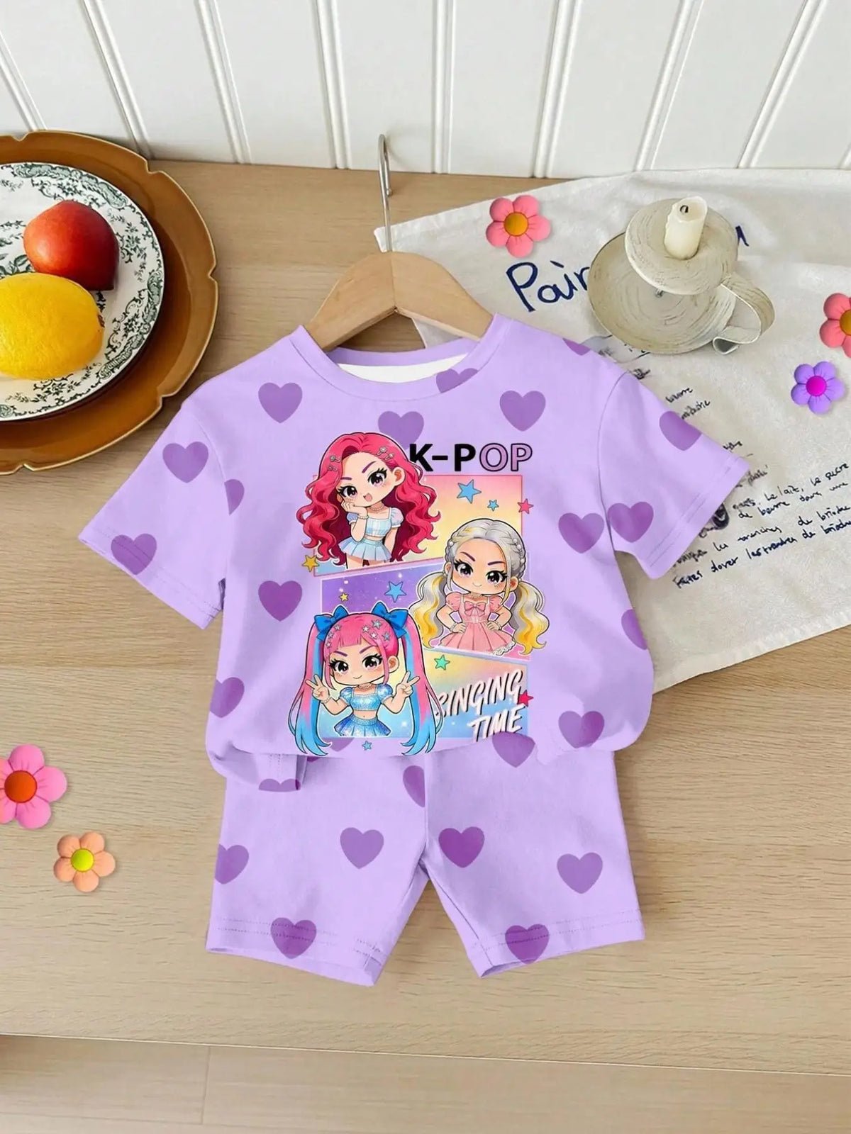 A purple two-piece summer set for girls featuring a K-Pop themed heart print on the shirt and shorts.