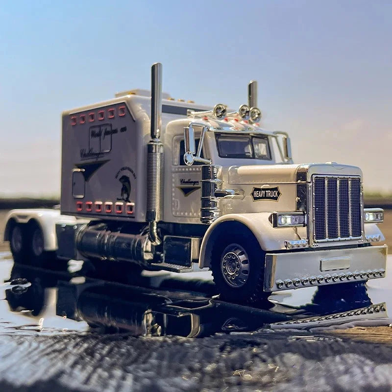 A silver Peterbilt 389 diecast truck model with lights and sound parked on a wet surface.