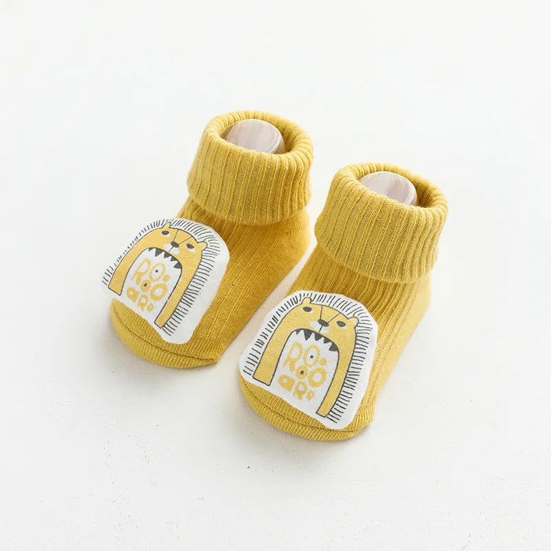 A pair of yellow cartoon non-slip cotton socks for babies and toddlers featuring a lion face design.