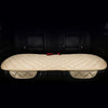 A beige quilted car seat cushion set with a padded back and seat, shown inside a dark car interior.