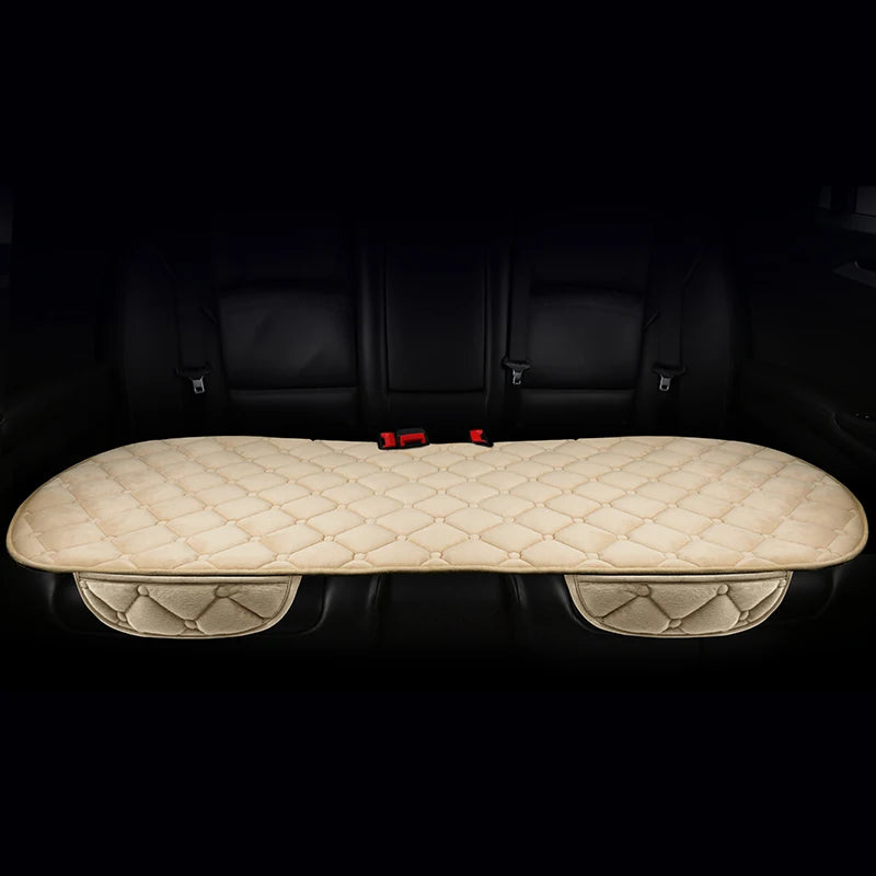 A beige quilted car seat cushion set with a padded back and seat, shown inside a dark car interior.