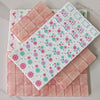 A set of pink acrylic Mahjong tiles arranged in a grid on a white surface.