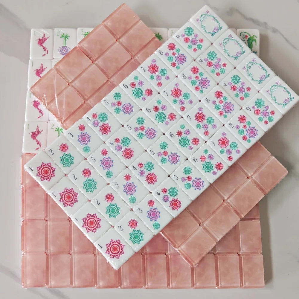 A set of pink acrylic Mahjong tiles arranged in a grid on a white surface.