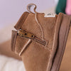 A close-up of a brown suede winter snow boot for toddlers with a zipper detail.