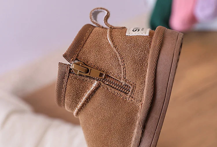 A close-up of a brown suede winter snow boot for toddlers with a zipper detail.