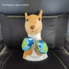 A plush toy resembling a dog or fox with light brown fur and blue patterned balls, displayed on a dark couch.