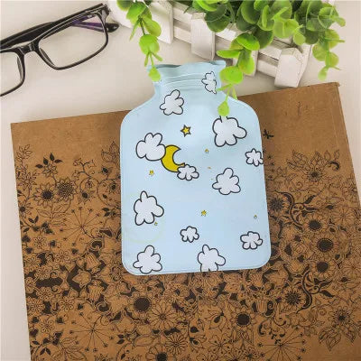 A light blue portable hot water bottle with a cloud and moon design resting on brown kraft paper.