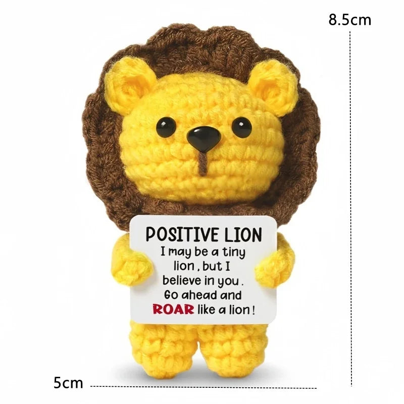 A yellow crochet lion doll with brown fur and a positive message card.