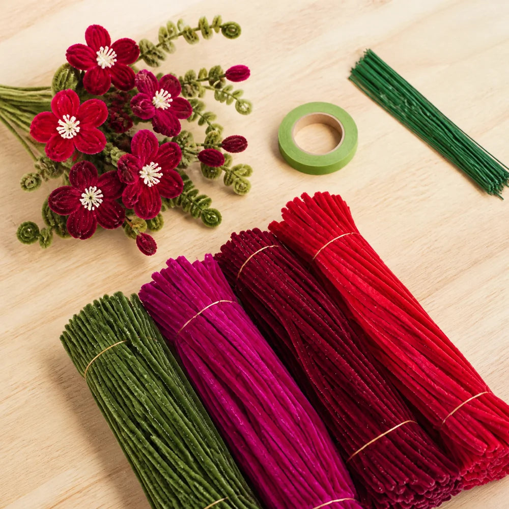 A collection of 400 chenille stems in mixed colors, including red, magenta, and green, laid out on a wooden surface.