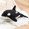 A black and white plush toy depicting a killer whale and a great white shark resting on a white fluffy surface.
