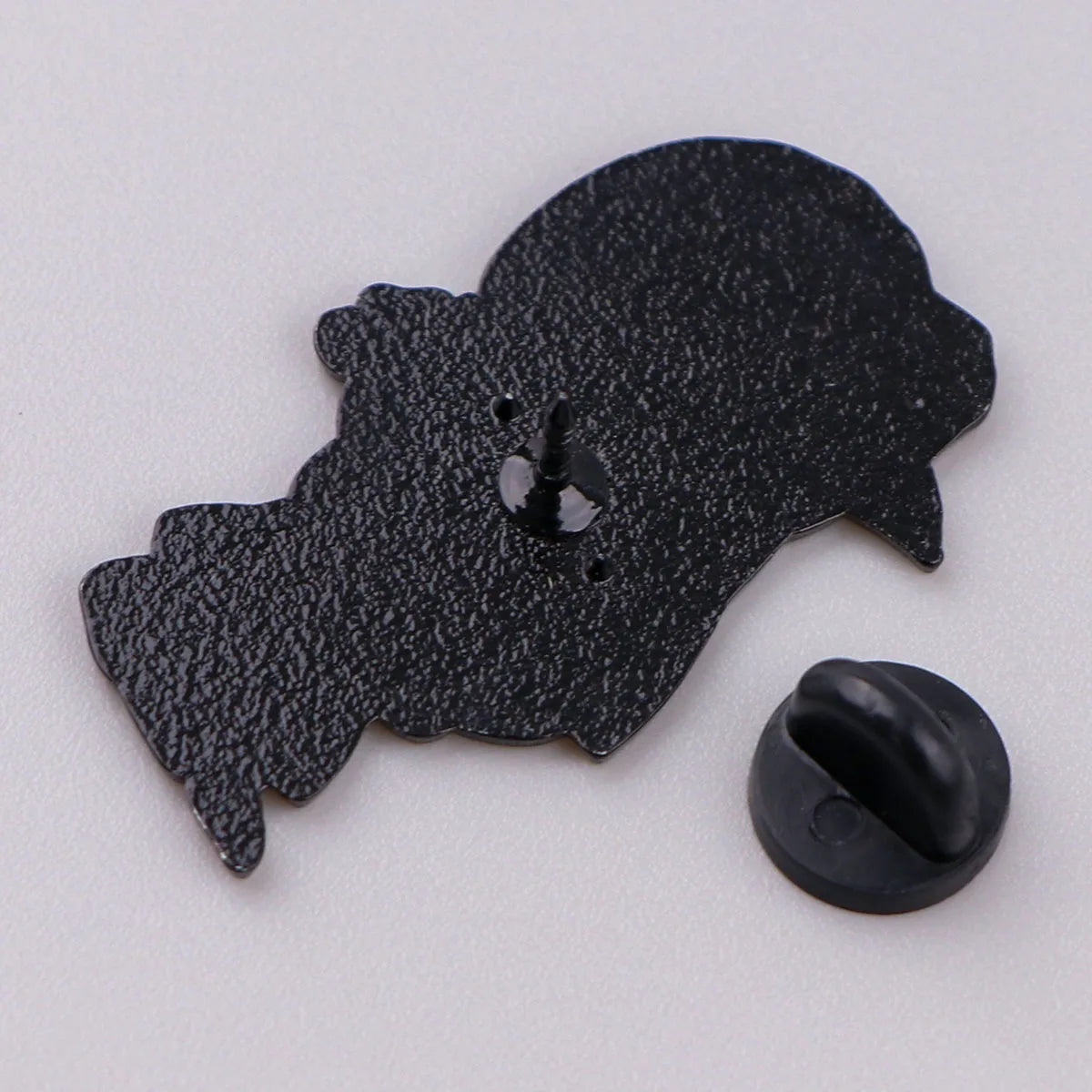 A black enamel pin shaped like a cartoon dog head.