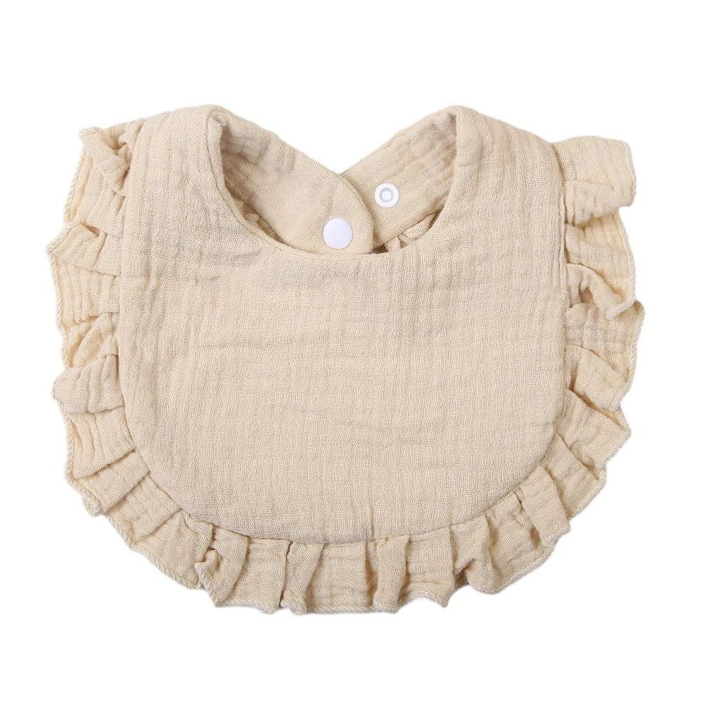 A light beige ruffled muslin cotton baby bib with an adjustable snap closure.
