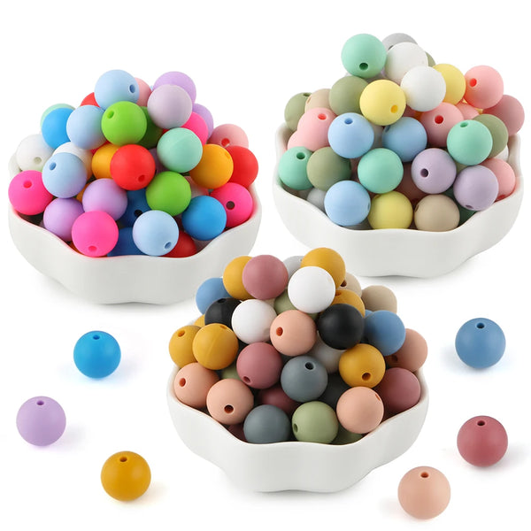 A collection of colorful silicone round beads in various shades and sizes displayed in white bowls.