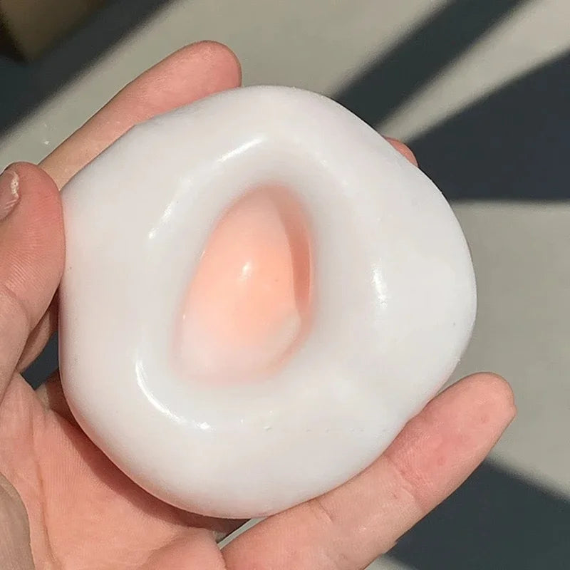 A hand holds a white, squishy stress relief ball with a translucent pink center.