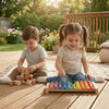 Two children play with wooden handle handpan drum mallets and silicone tips on a wooden floor.