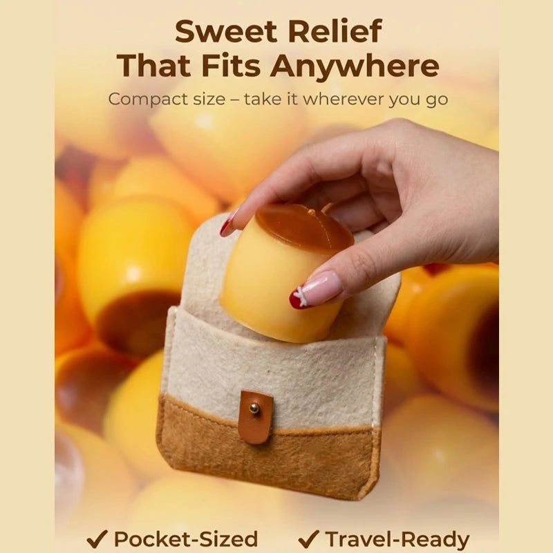 A hand holds a small, yellow caramel pudding squishy stress relief ball in a beige fabric pouch.