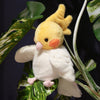 A fluffy yellow parrot plush toy with pink feet perched on green leaves.