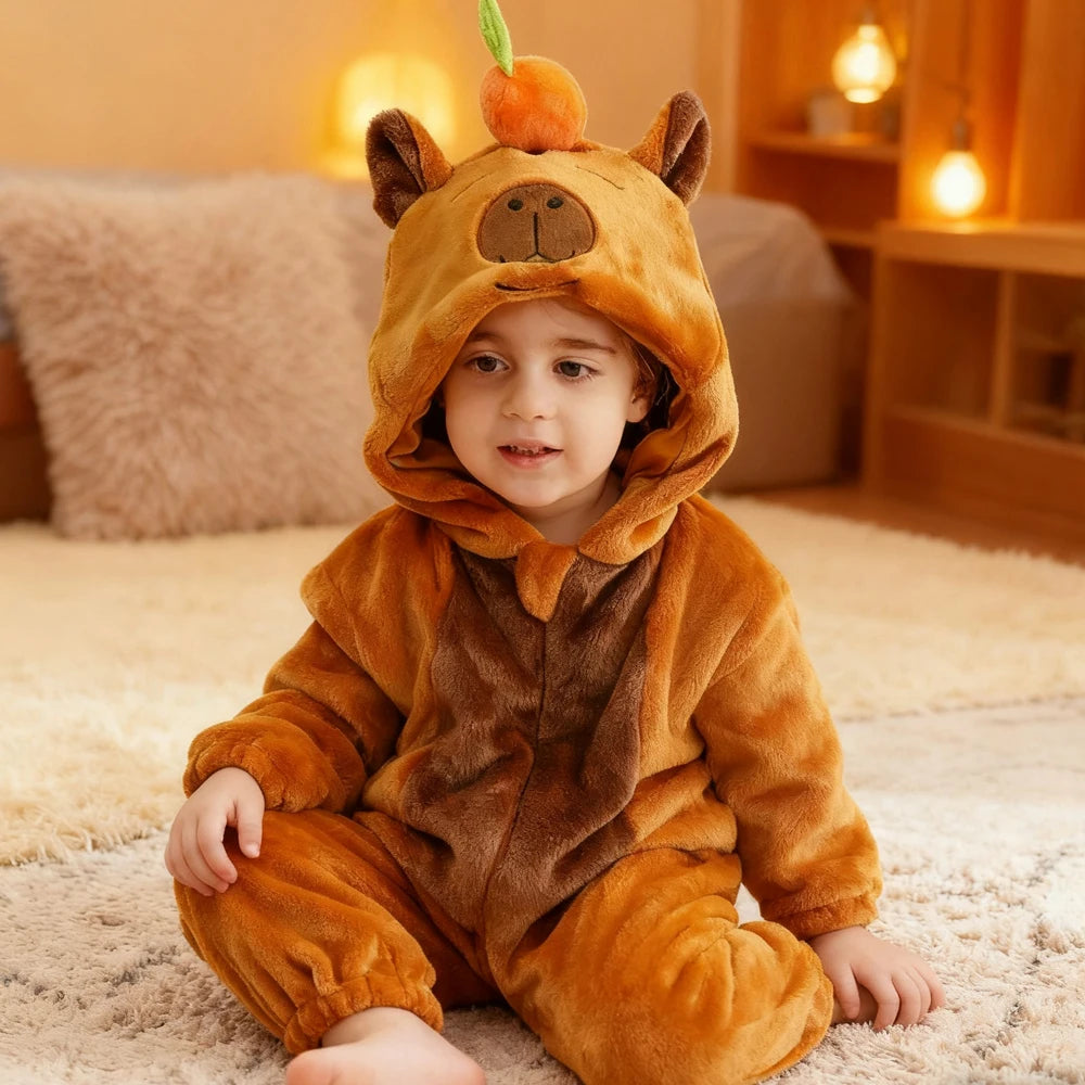 A baby wearing an adorable orange-brown animal hooded romper sitting on a light rug.