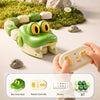 A green snake toy is shown next to its remote controller and stickers on a light surface.