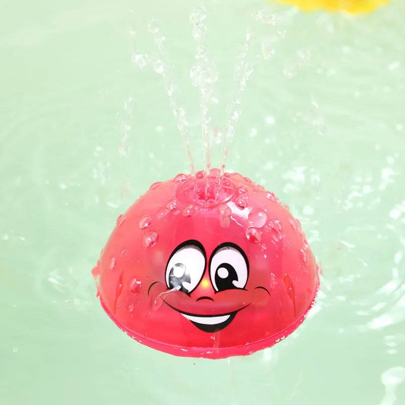 A bright pink, spherical bath toy with a smiling face is being sprayed with water.