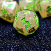 A close-up of a green resin polyhedral dice set with numbers and floral designs resting on a dark surface.