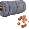 A spool of gray natural cotton macrame rope with several finished knots scattered below.