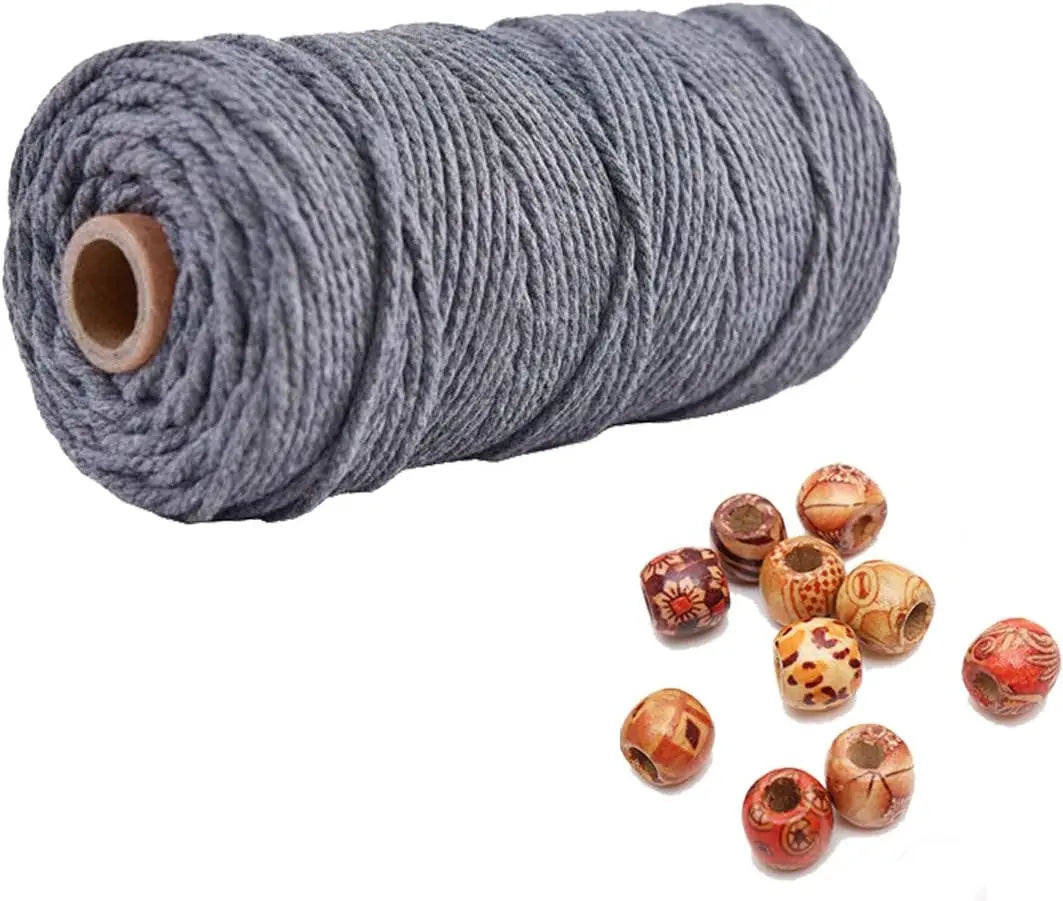 A spool of gray natural cotton macrame rope with several finished knots scattered below.