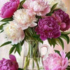 A bouquet of pink and purple peonies and roses arranged in a glass vase on a white surface.