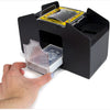 A hand is inserting a deck of cards into a black automatic card shuffler device.