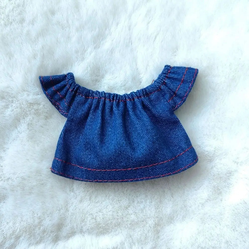 A navy blue ruffled top for a fashion doll, featuring red stitching details.