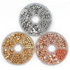 A collection of gold and silver plated beads for jewelry making, displayed in circular trays.