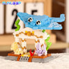 A LEGO-style building block set featuring a blue shark, crab, and clownfish figures built on a wooden base.