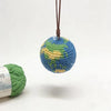 A handcrafted crochet earth keychain charm with a blue and green textured sphere suspended by a brown leather cord.