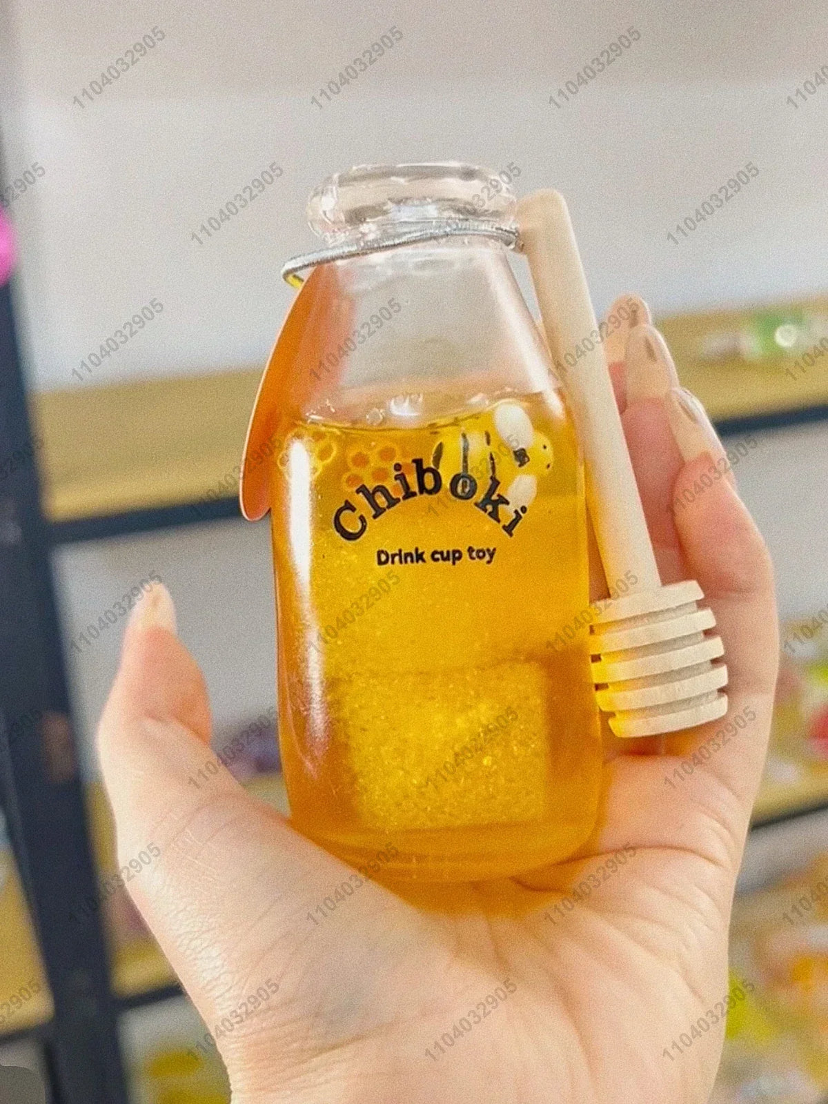 A hand holds a clear bottle filled with yellow liquid labeled Chiboki drink cup toy