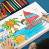 A child is drawing a sailboat on a page of a kids drawing and coloring book.