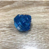 A small, translucent blue gyro driver for spinning tops resting on a wooden surface.