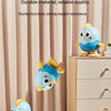 A blue cartoon chick wind-up toy is displayed on a wooden dresser against a light curtain backdrop.