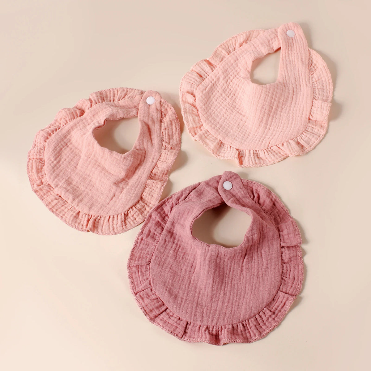 A set of eight pink cotton ruffle baby bibs laid out on a light background.