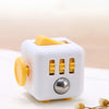 A white fidget cube with a rotating joystick, magnetic buttons, and a silver sphere on a wooden surface.
