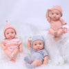 A collection of realistic soft vinyl reborn baby dolls dressed in pink and gray clothing sitting on white fluffy material.